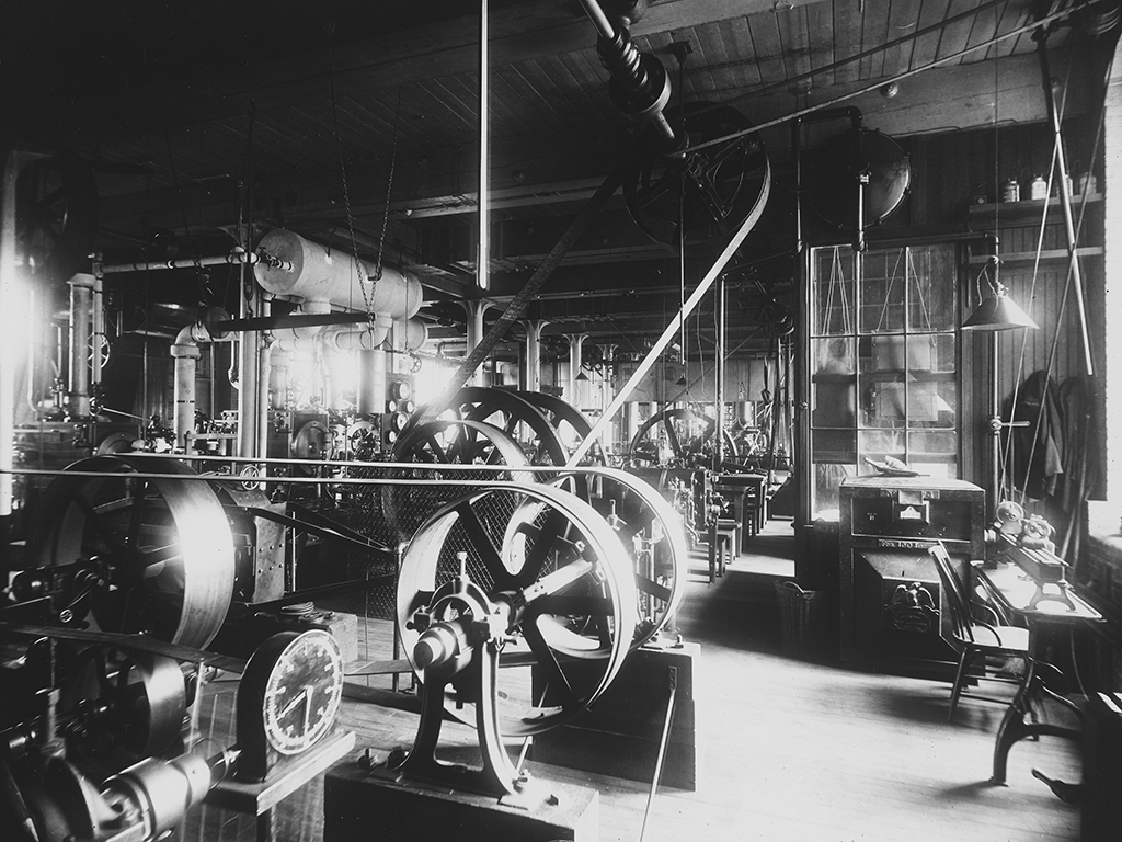 A black and white image of a large engine with a big wheel.