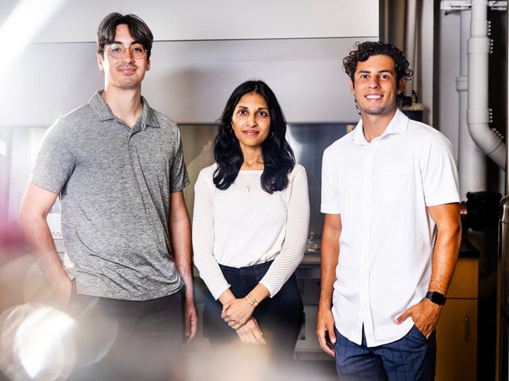 Angel Bu, Ritu Raman, and Brandon Rios stand in the lab, with blurry light in foreground.