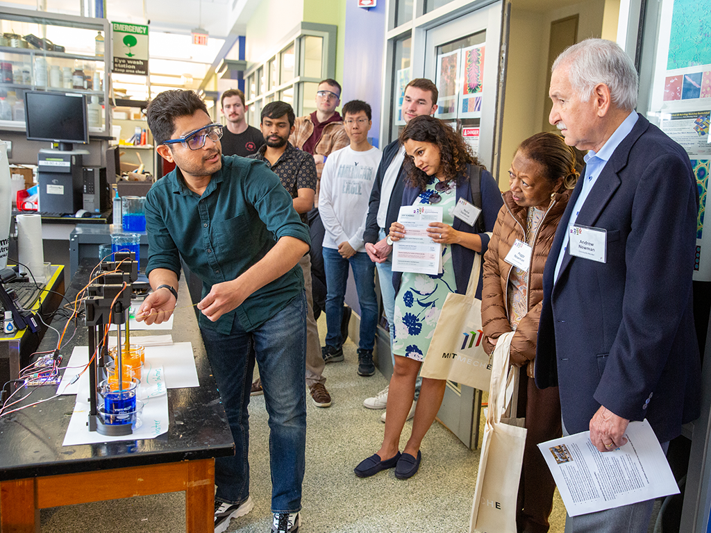 An image of a student showing a research project to faculty. 